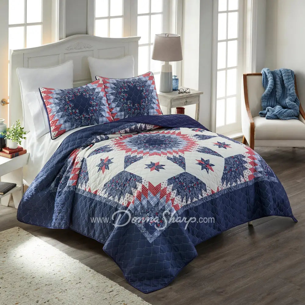 Donna Sharp Bluefield Star quilt set styled on bed with navy floral border, country blue, periwinkle, pale ivory, rose, and raspberry Lone Star pattern, and matching pillow shams