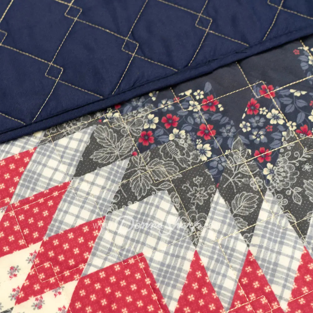 Close-up of Donna Sharp Bluefield Star quilt showing intricate patchwork with navy floral print, country blue, periwinkle, pale ivory, rose, and raspberry, diamond quilting stitches