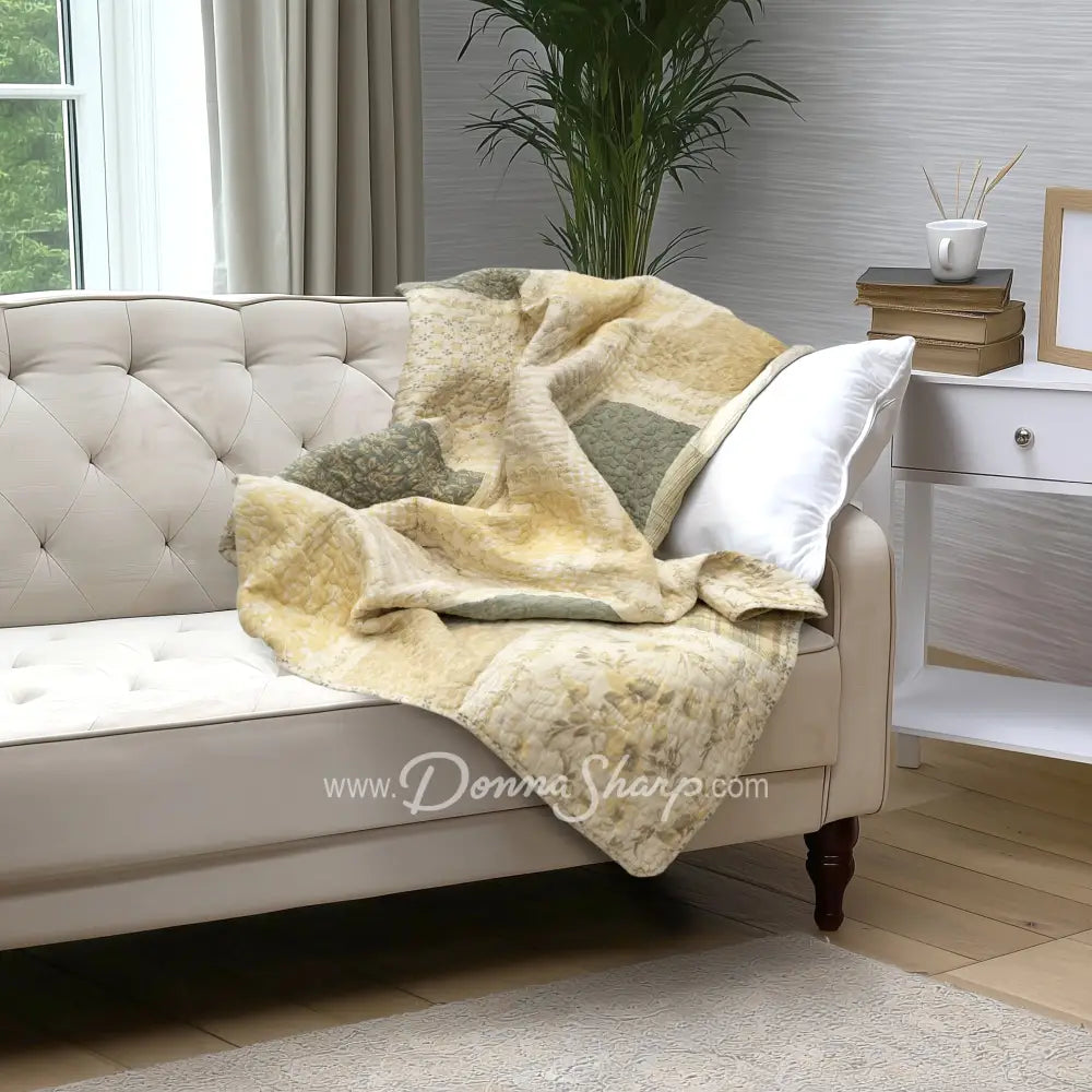 Donna Sharp Meadow cotton patchwork throw blanket draped on tufted sofa in modern farmhouse living room with sage green and cream floral patterns