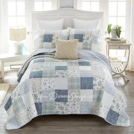 Donna Sharp Blue Pastures cotton patchwork quilt set styled on bed in coastal farmhouse bedroom with soft blues, gentle creams, and crisp white floral and plaid blocks
