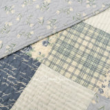 Close-up of Donna Sharp Blue Pastures cotton quilt showing patchwork blocks with soft blues, gentle creams, and crisp whites rose patterns with diamond quilting