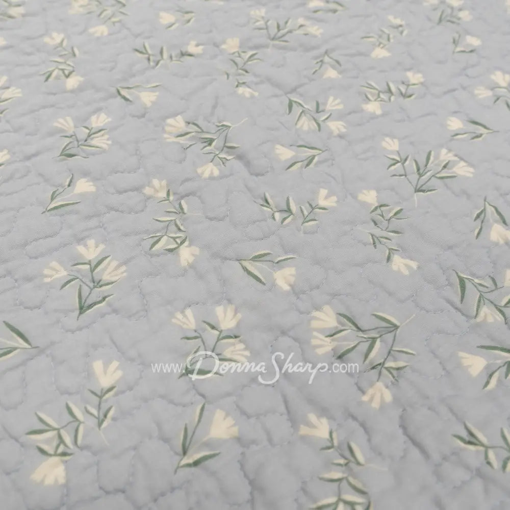 Close-up of Donna Sharp Blue Pastures cotton quilt reverse fabric showing soft gray background with delicate cream floral sprigs 