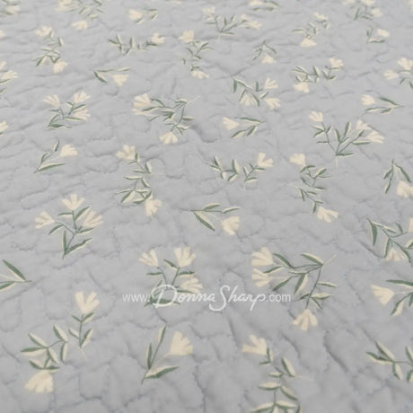 Close-up of Donna Sharp Blue Pastures cotton quilt reverse fabric showing soft gray background with delicate cream floral sprigs 