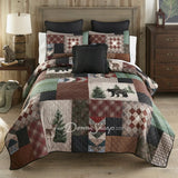 Donna Sharp Greenwood Patch quilt set styled on bed in rustic lodge bedroom with bear, deer and pine tree appliques in sage, deep olive, warm browns, muted terracotta, hints of denim and spruce blue, and aged parchment ivories and tans patchwork