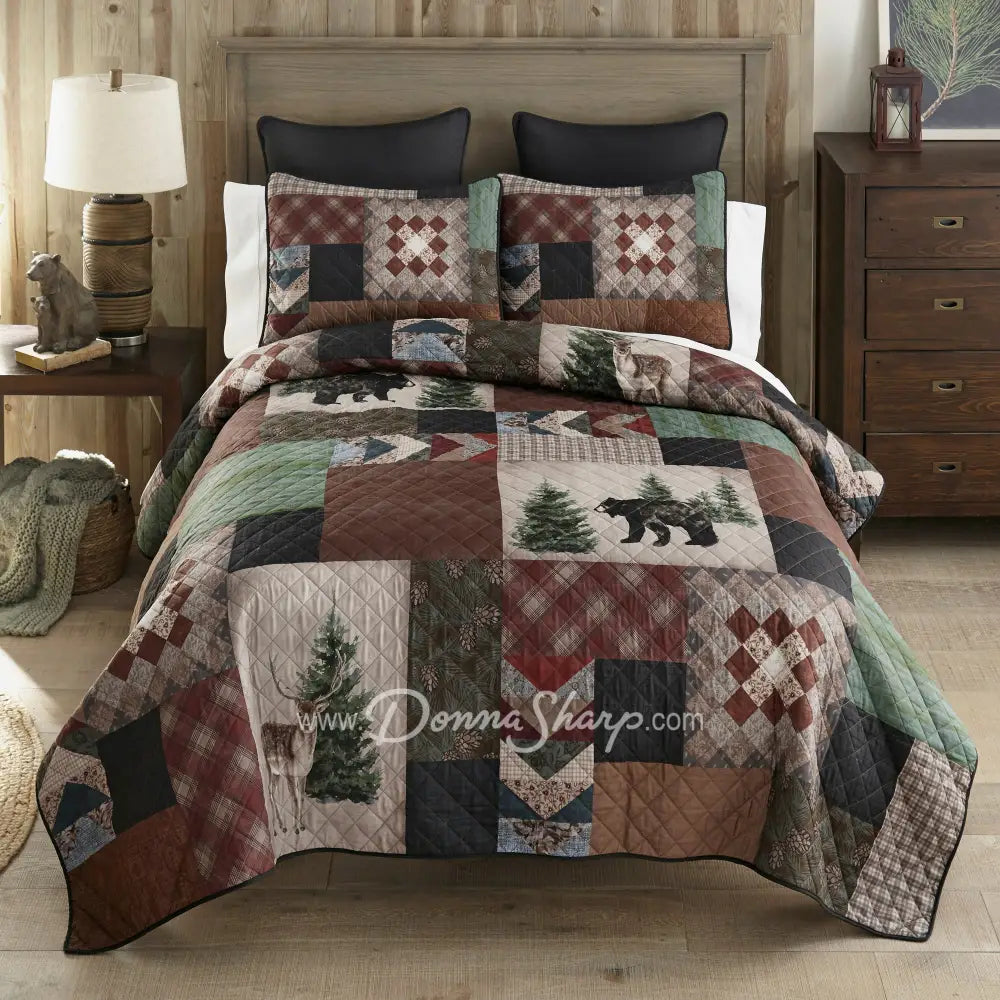 Donna Sharp Greenwood Patch quilt set styled on bed in rustic lodge bedroom with bear, deer and pine tree appliques in sage, deep olive, warm browns, muted terracotta, hints of denim and spruce blue, and aged parchment ivories and tans patchwork