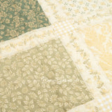 Close-up detail of Donna Sharp Meadow cotton patchwork quilt showing soothing shades of sage green, beige, white, buttercream gold, and cream floral fabric blocks with quilting stitches